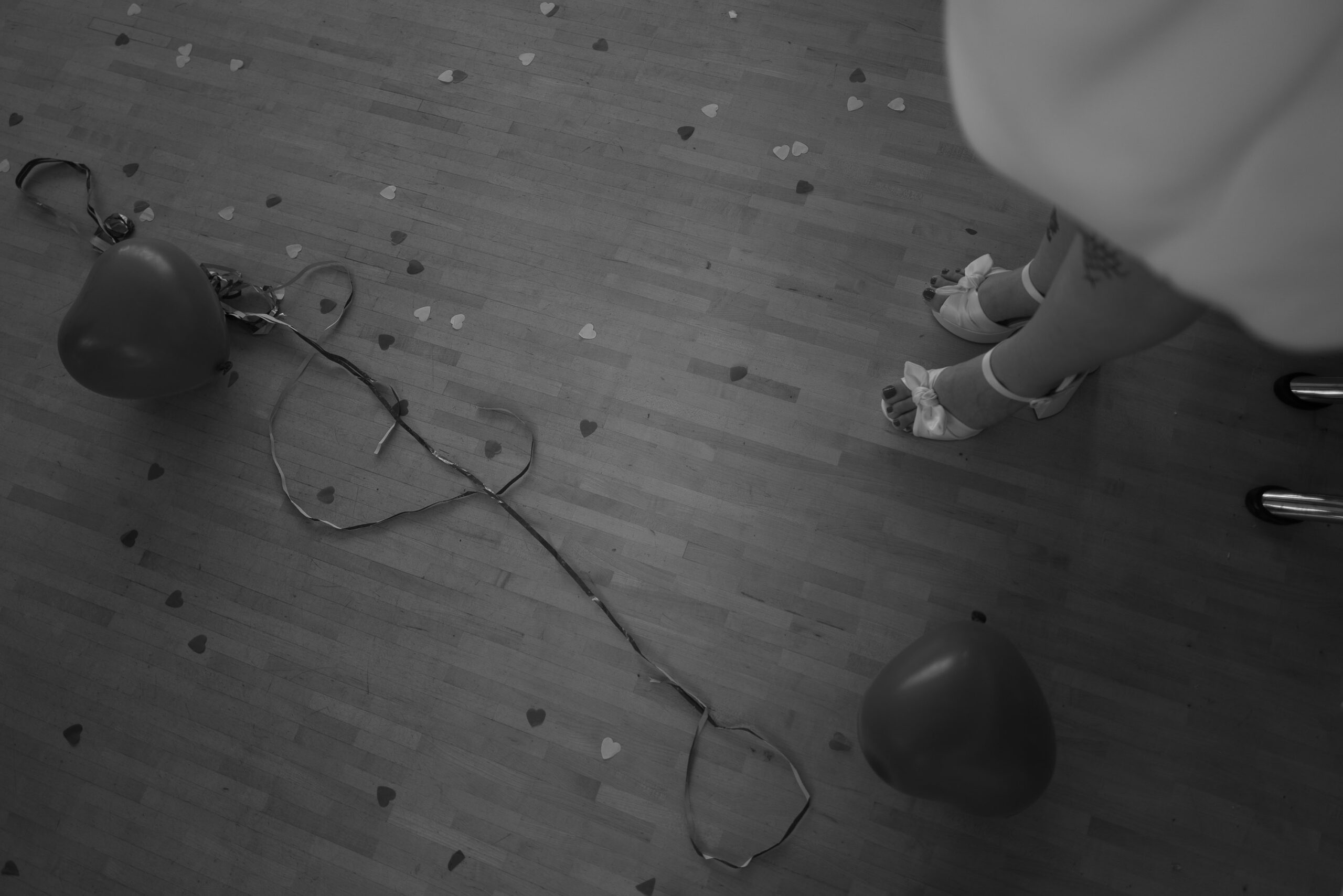 Braut in Plateau-Sandalen neben Luftballons & Partyresten – ungestellte Hochzeitsreportage nach der Party.