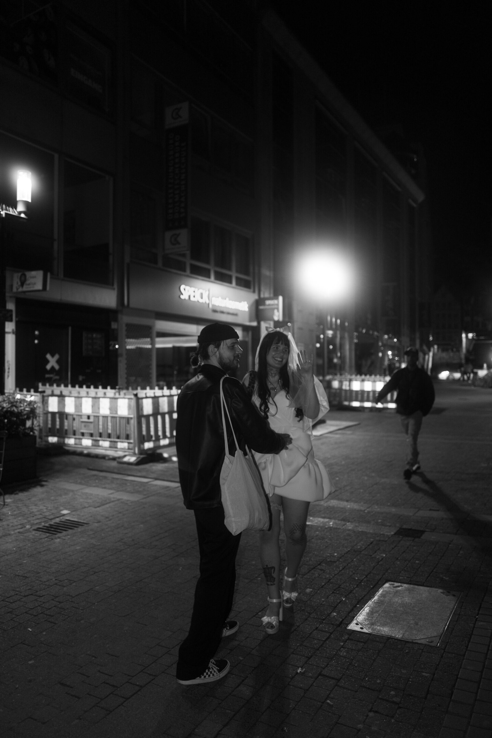 Ein frisch verheiratetes Paar teilt einen Kuss in einer dunklen Straße in Stuttgart.