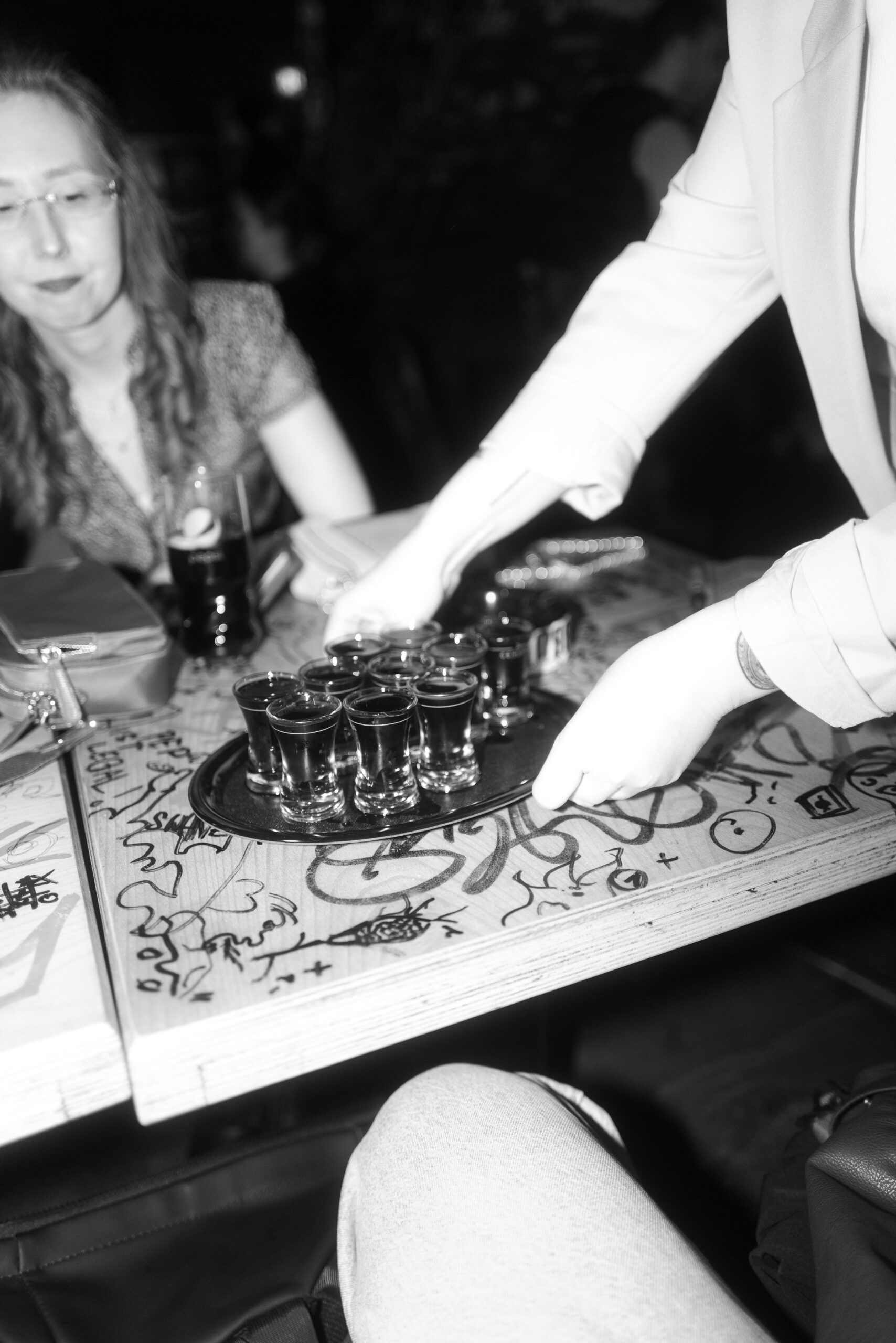 Tablett mit Schnapsgläsern auf einer wilden Hochzeitsfeier, ausgelassene Stimmung in einer Bar.