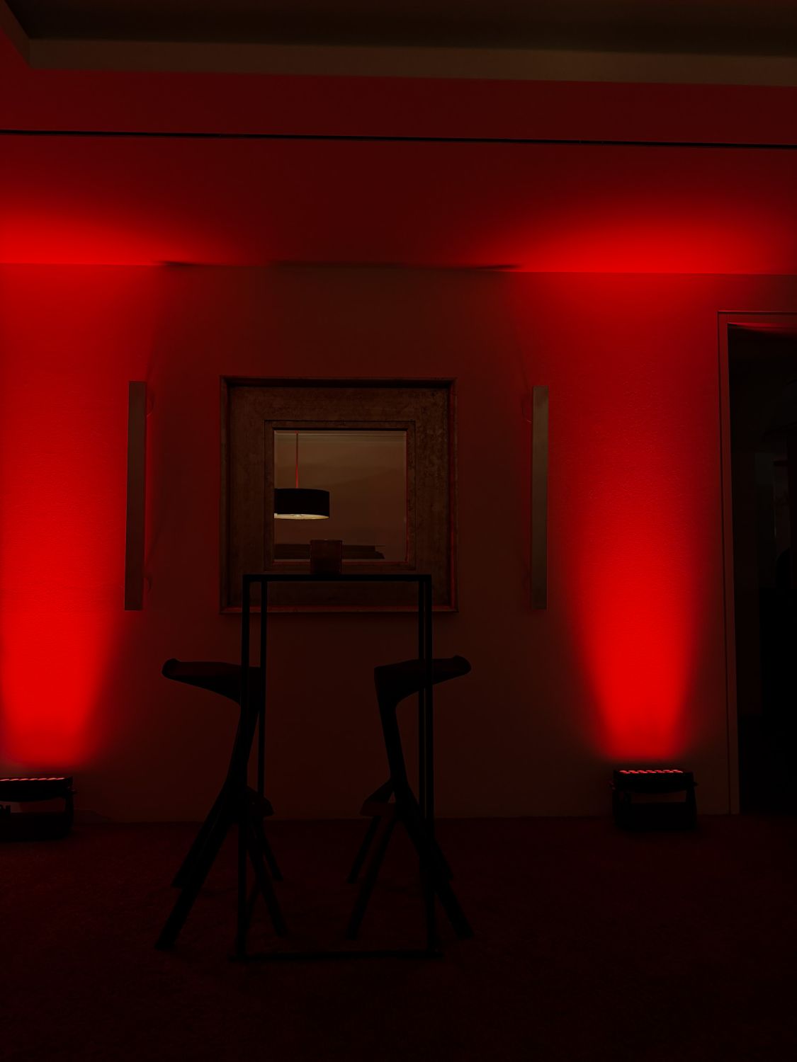Rot ausgeleuchtete Location mit Hockern und Spiegel – stimmungsvolle Hochzeitsszene in München.