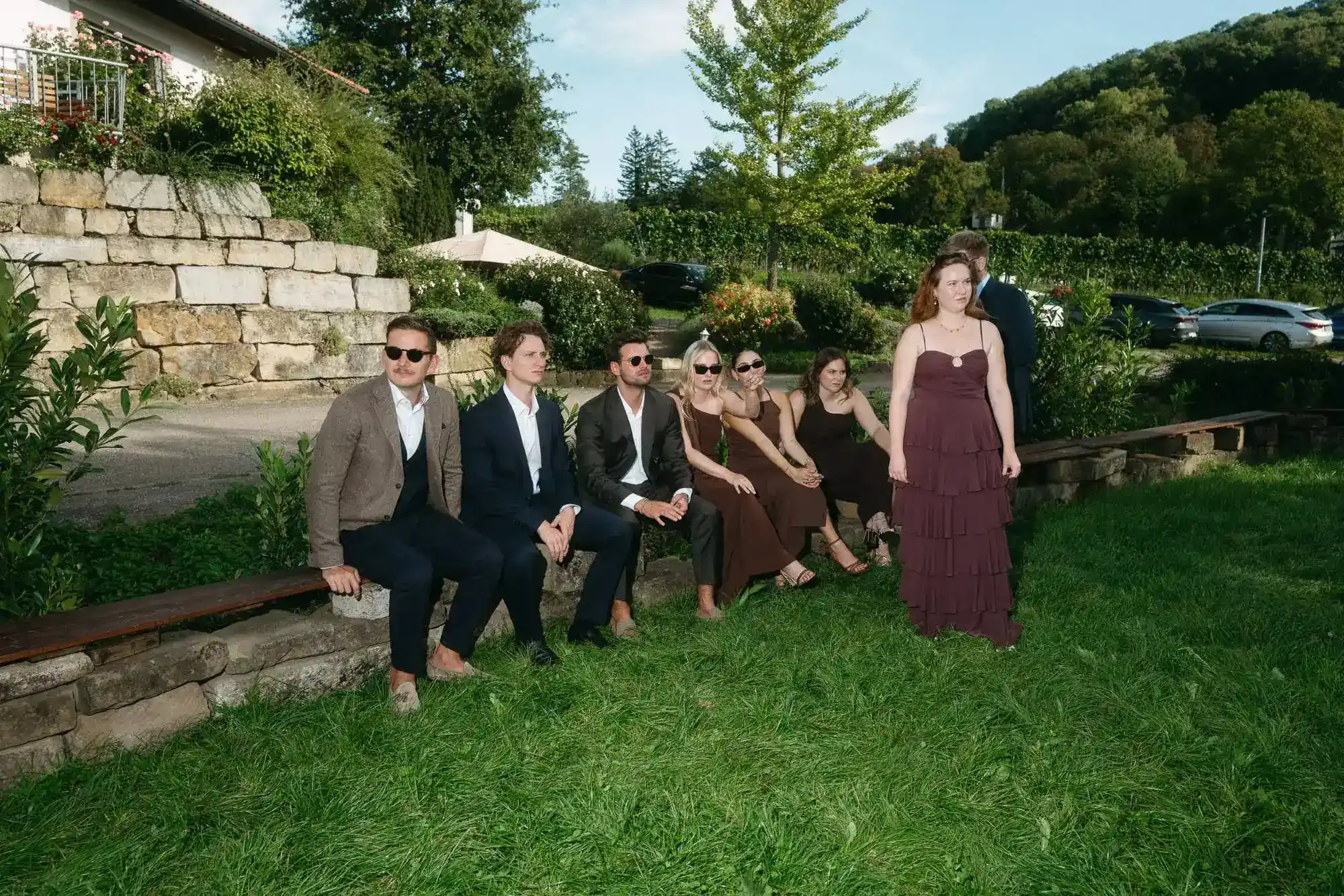 hochzeitsgäste sitzen entspannt im garten – sommerliche atmosphäre und echte momente in moderner dokumentarischer hochzeitsfotografie
