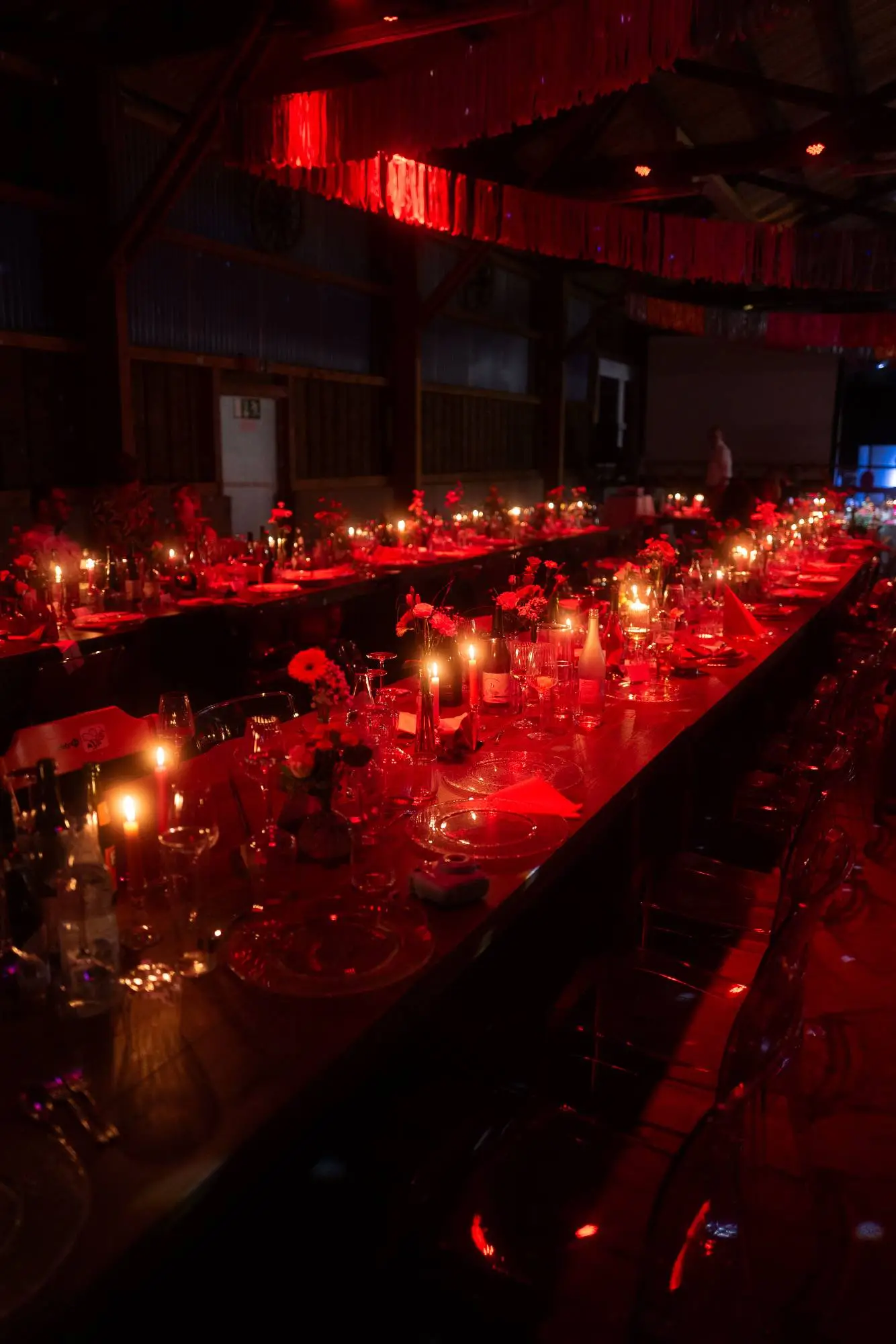 Festlich gedeckter Hochzeitstisch in rotem Licht mit Kerzenschein und floraler Dekoration – moderne dokumentarische Hochzeitsfotografie mit atmosphärischen Details.