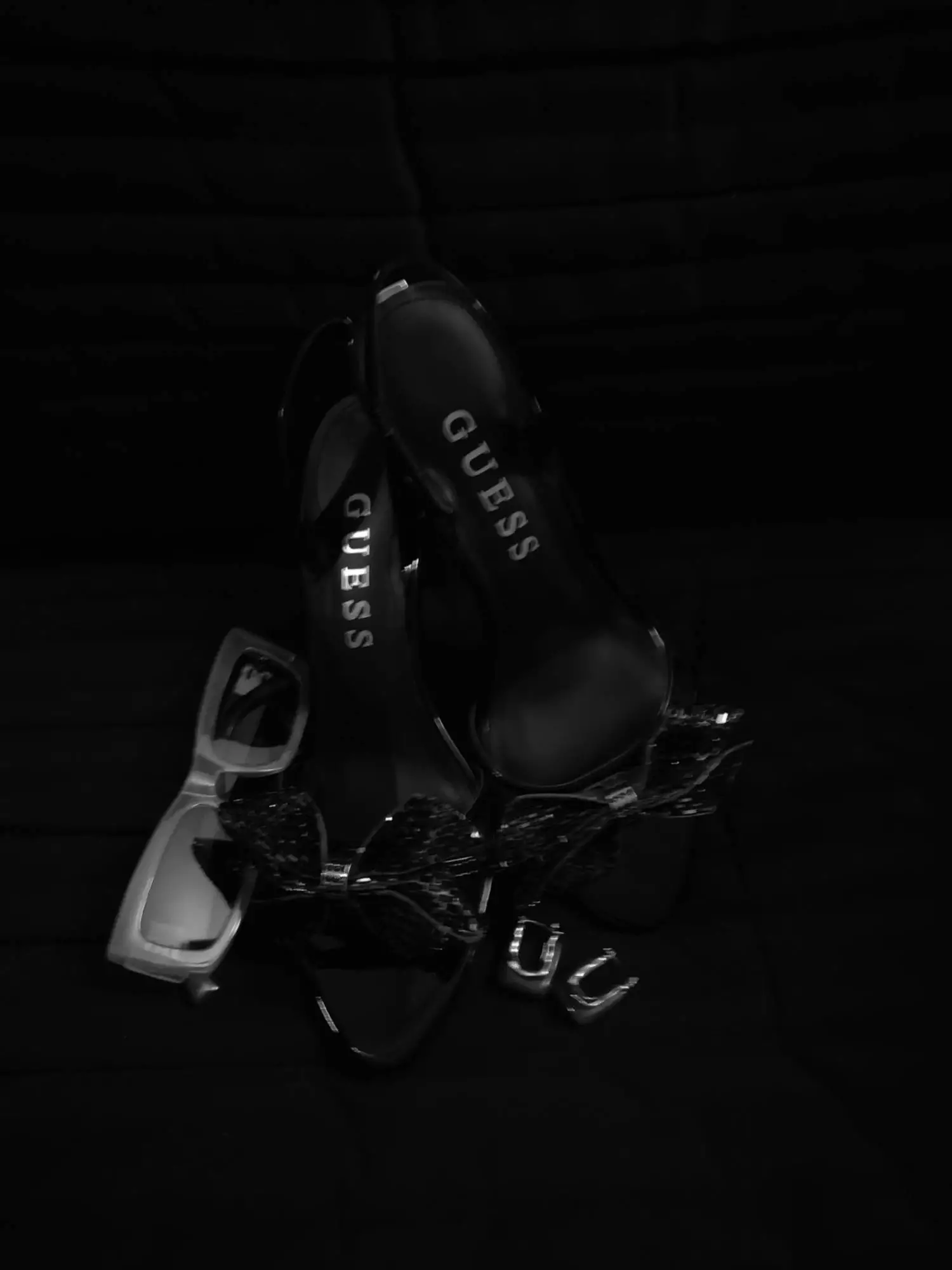 Schwarze High Heels, Schmuck und Sonnenbrille auf dunklem Untergrund – moderne dokumentarische Hochzeitsfotografie.