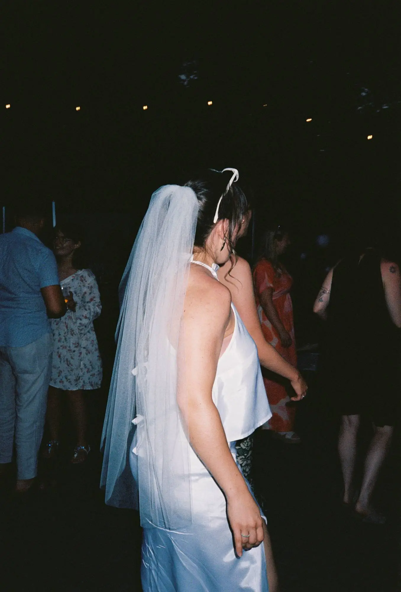 Braut in elegantem Seidenkleid tanzt ausgelassen auf der Hochzeit – moderne dokumentarische Hochzeitsfotografie mit Nähe und Gefühl.