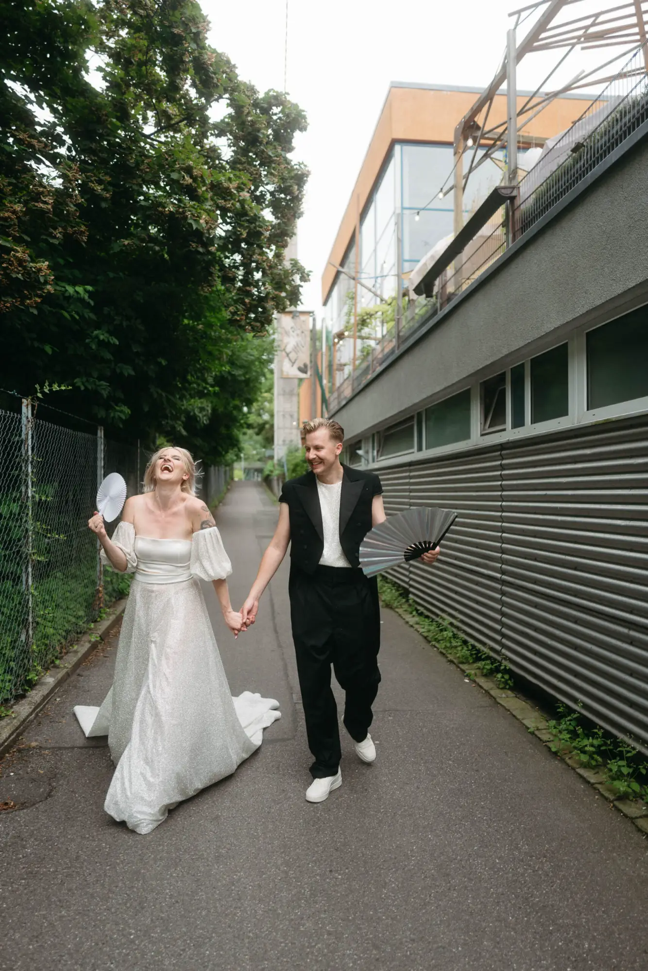 Moderne dokumentarische Hochzeitsfotografie – Menschen in Bewegung Ein Brautpaar läuft lachend durch eine urbane Gasse, ungestellt und dynamisch – moderne dokumentarische Hochzeitsfotografie, die echte Bewegung einfängt.