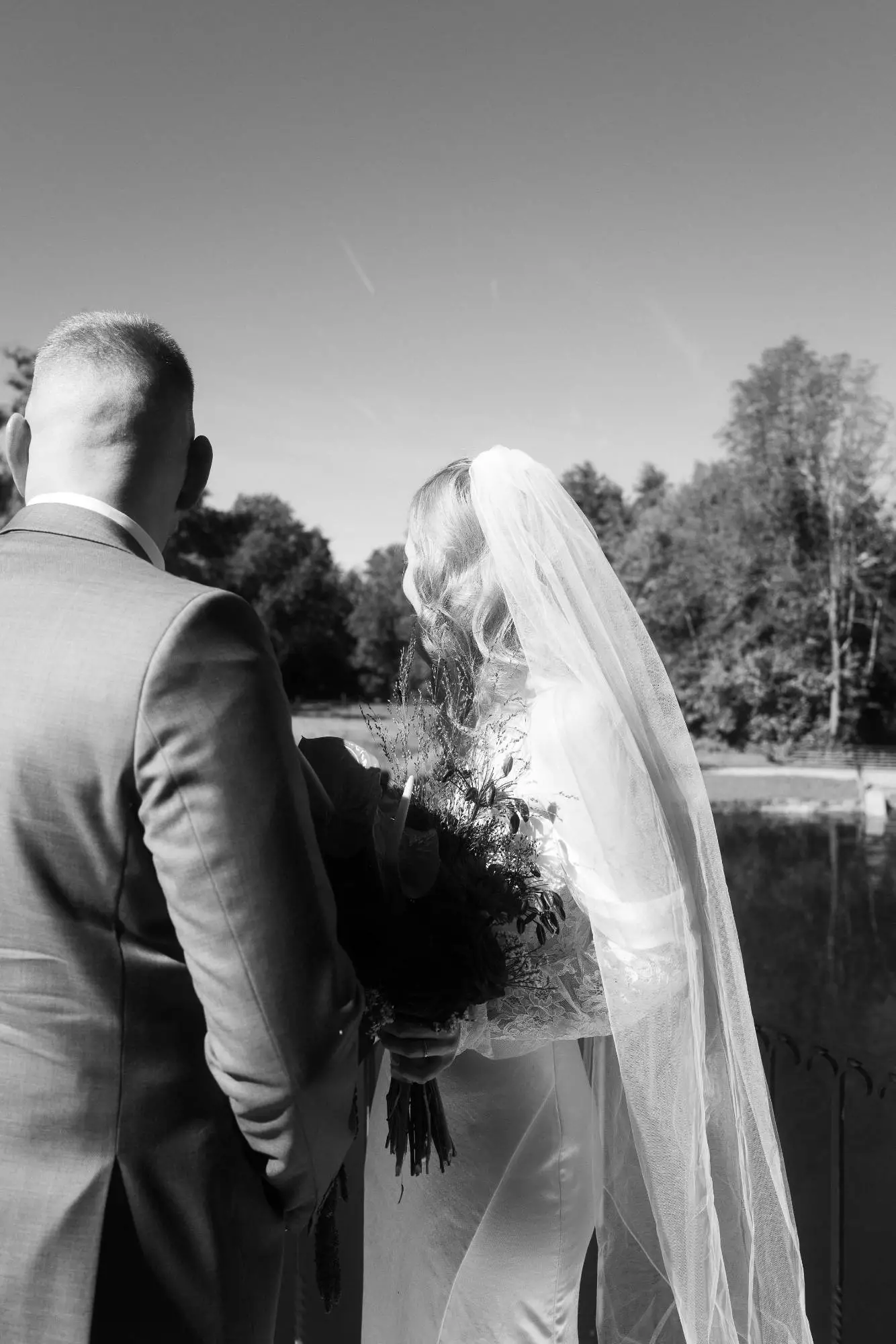 Ein stiller Moment zwischen Braut und Bräutigam – Rückenansicht, eingefangen in schwarzweiß. Die Ruhe vor dem nächsten Schritt, getragen von Licht, Schatten und Nähe.