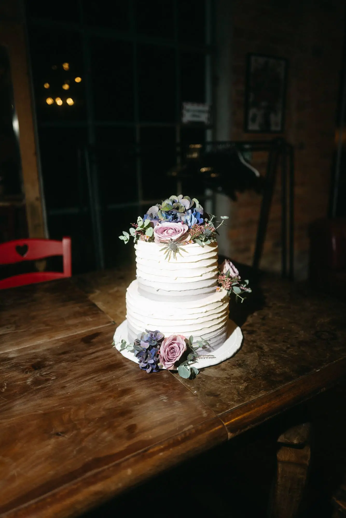 moderne dokumentarische hochzeitsfotografie mit natürlicher darstellung einer blumentorte auf rustikalem holztisch