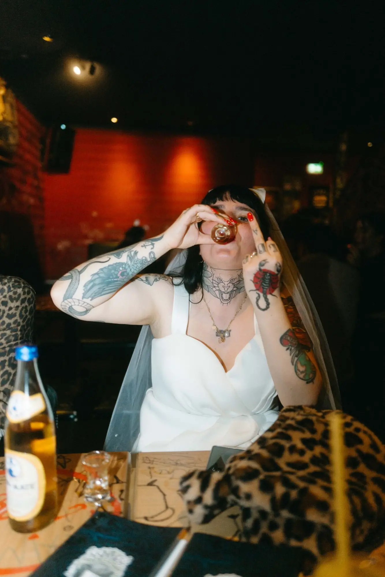 Braut mit Tattoos trinkt spontan einen Shot im Lokal – moderne dokumentarische Hochzeitsfotografie mit Nähe und Charakter