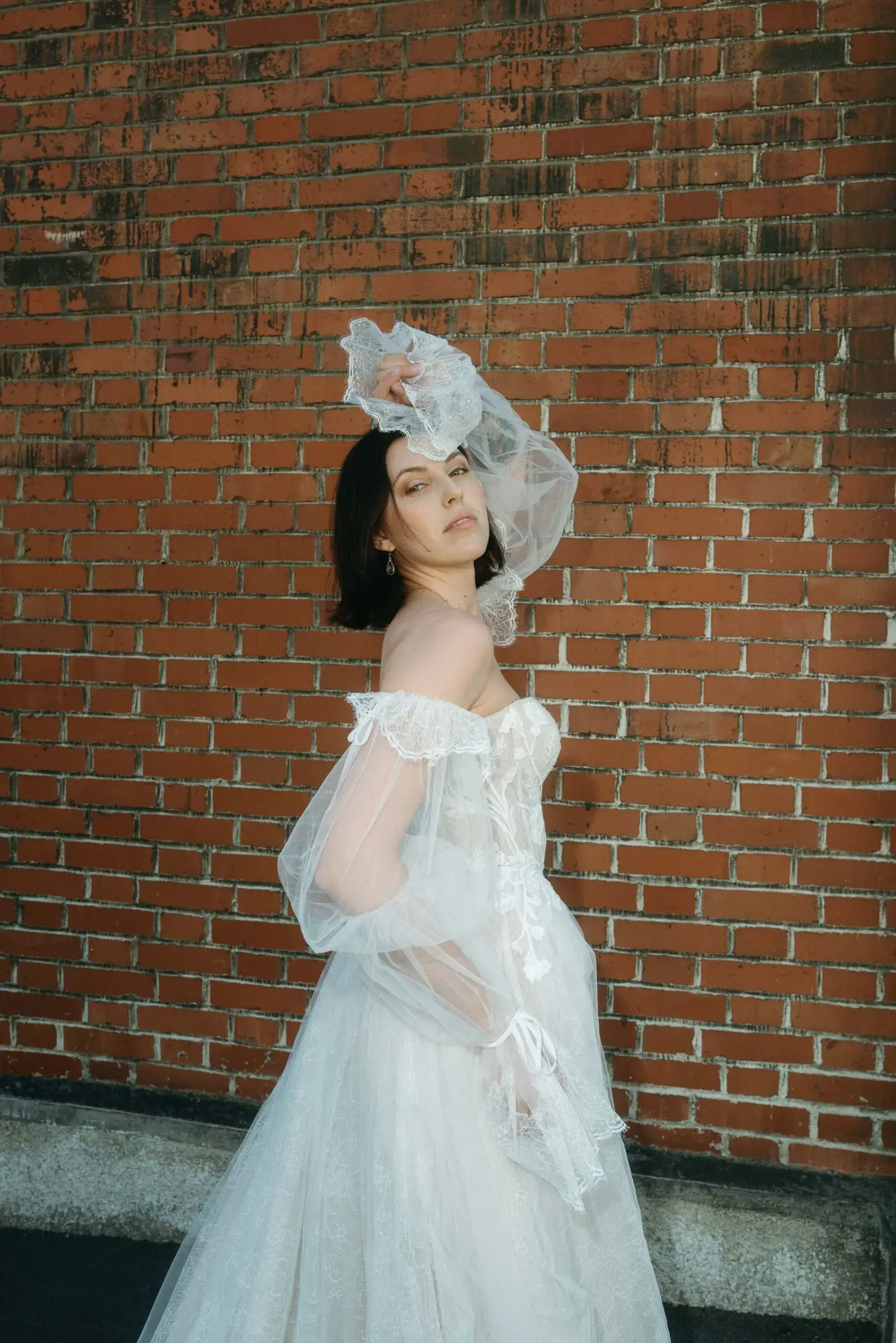 Ungeschützter Moment einer Braut vor einer Backsteinwand – moderne dokumentarische Hochzeitsfotografie mit mutigem Ausdruck und ehrlicher Präsenz