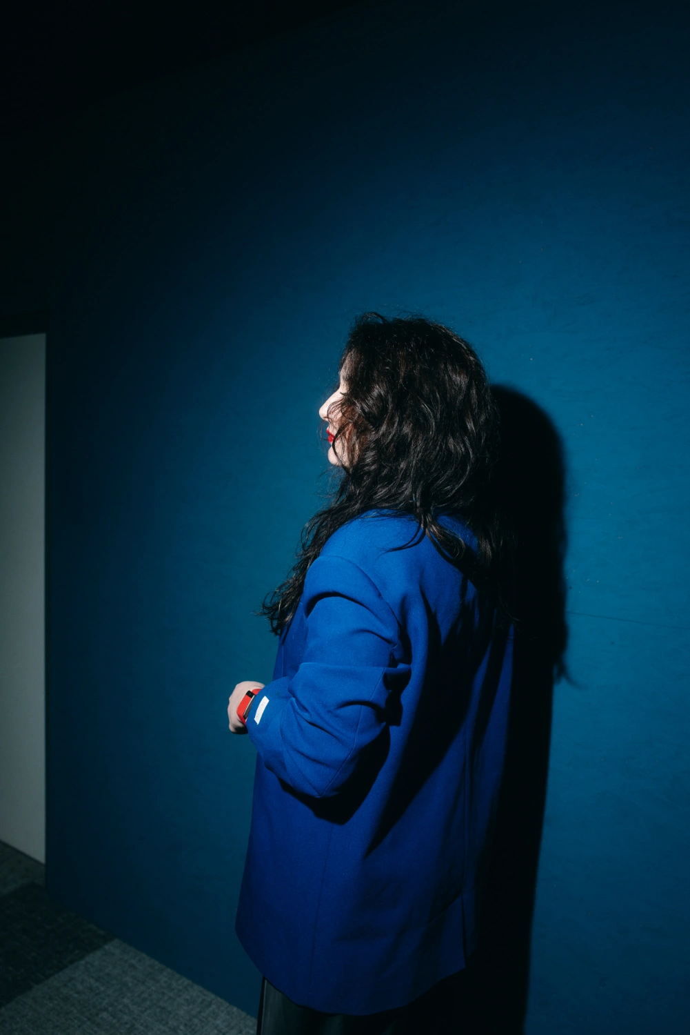 moderne-brand-fotografie-stuttgart-business-portrait-blauer-blazer Moderne Brand Fotografie in Stuttgart: Frau im blauen Blazer als seitliches Business-Portrait vor dunkler blauer Wand.